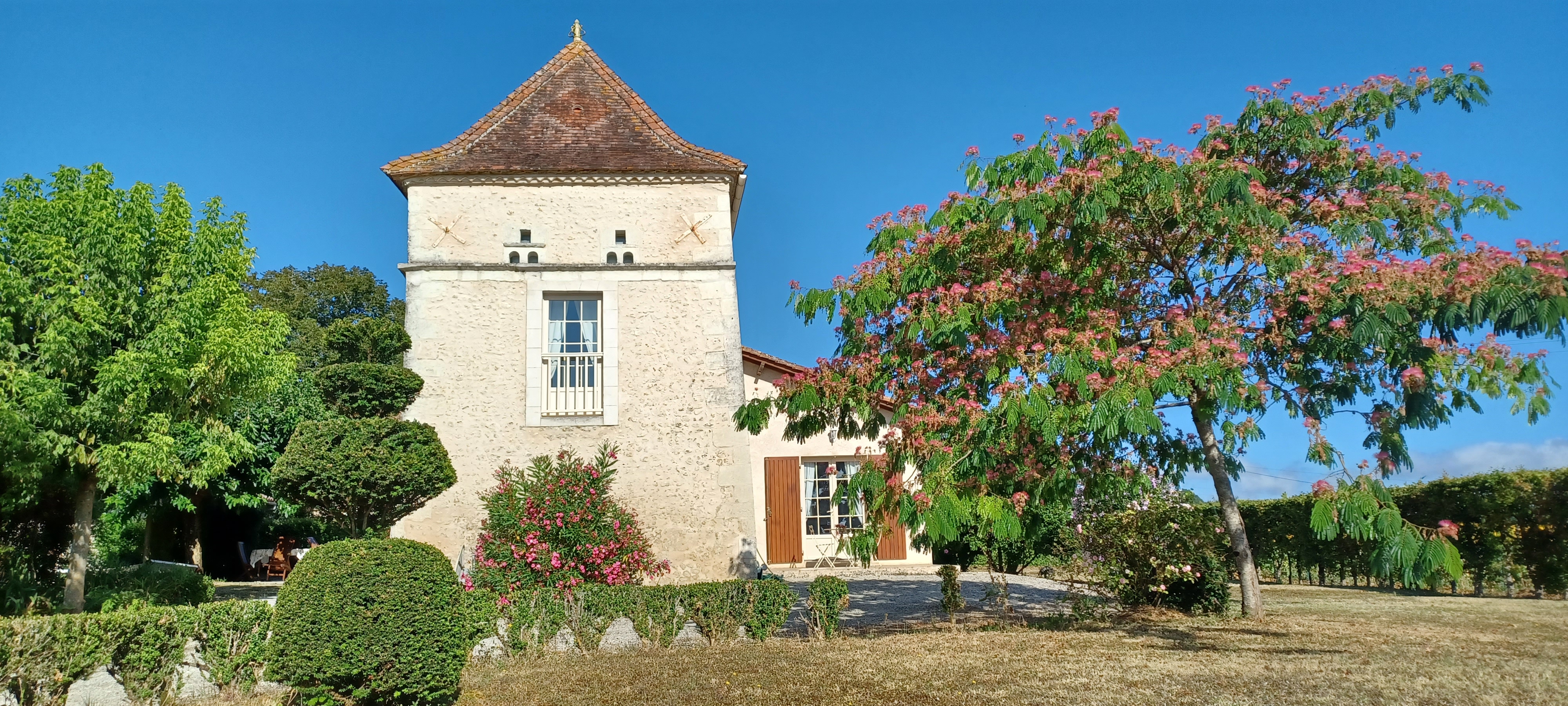 Le Pigeonnier — façade en pierre et jardin fleuri