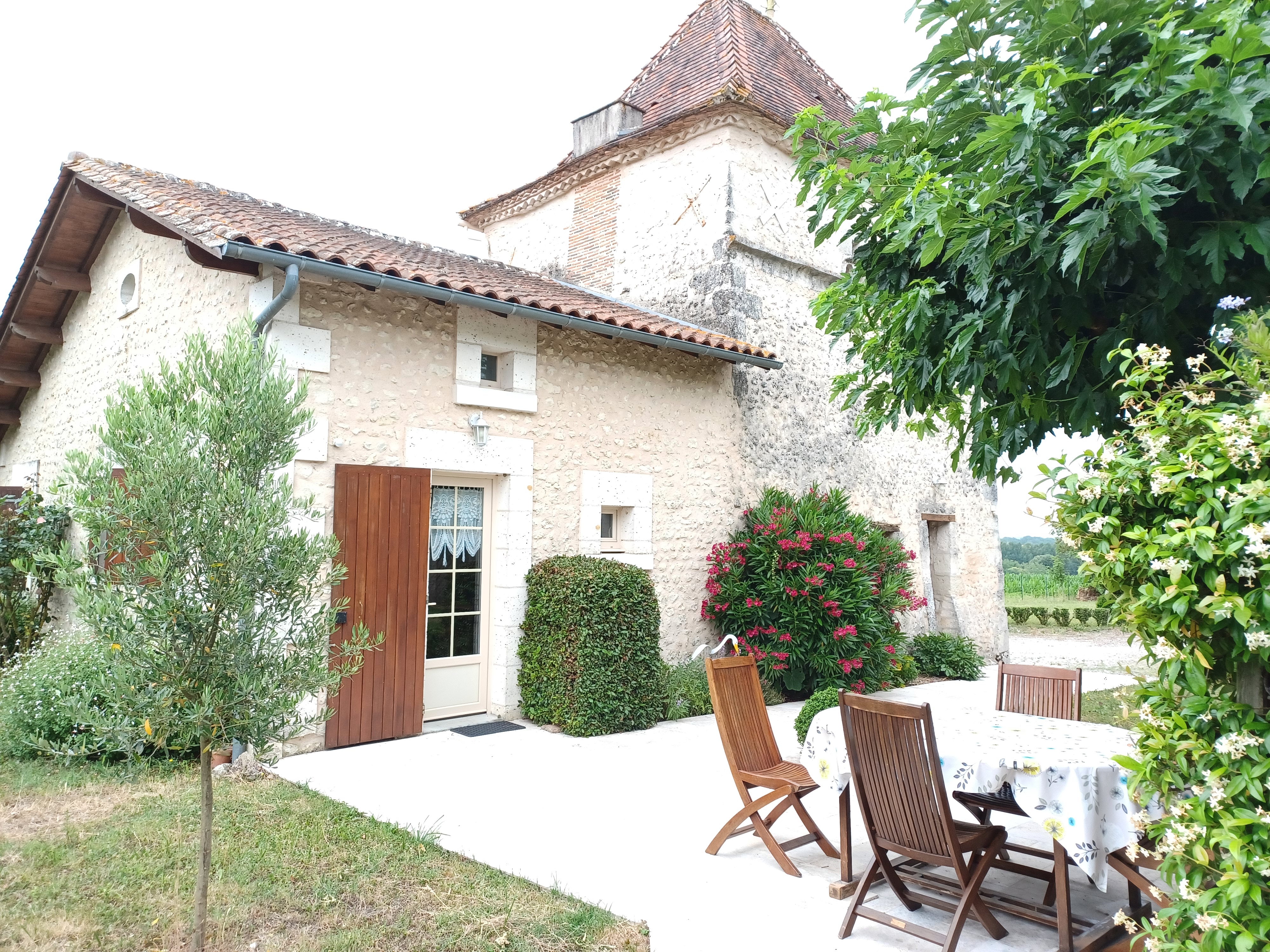 Terrasse en pierre avec salon de jardin, façade du pigeonnier